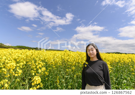 A woman sightseeing in a field of rapeseed flowers in full bloom 126867562