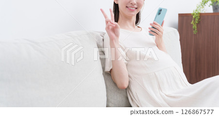 Pregnant woman using a smartphone (peace sign) 126867577