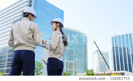 A group of male and female engineers having a meeting while looking at a tablet at a construction site 126867753