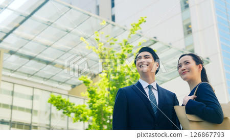 站在綠樹成蔭的城市中的男女商人 站在綠樹成蔭的城市中的男女商人 126867793