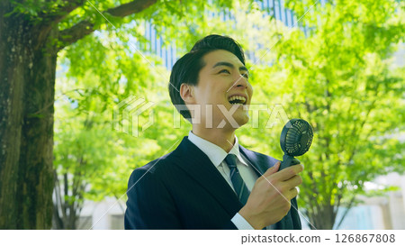 Male business person cooling off with a portable fan 126867808