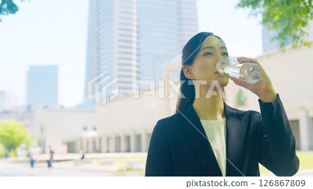 Female business person drinking water in the city 126867809