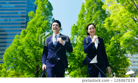 男女商人奔跑在綠樹成蔭的城市中 126867819