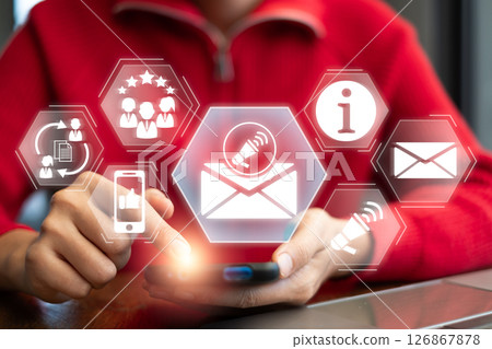 A person interacts with digital newsletter icons on a smartphone, symbolizing modern communication and information sharing. 126867878