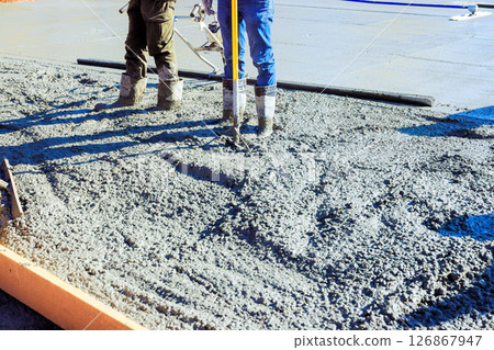 Construction workers pouring concrete to foundation at residential site on works day for building Construction workers pouring concrete to foundation at residential site on works day for building 126867947