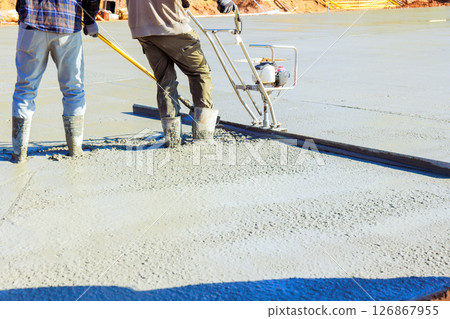 Contractor use screed to level freshly poured concrete on construction site in broad works day 126867955