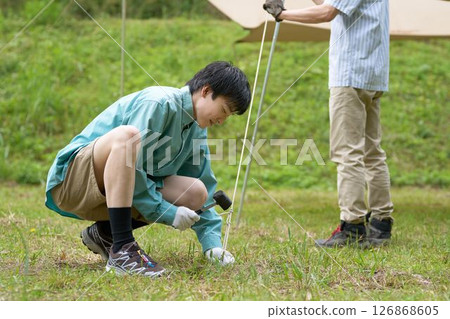 Camping friends setting up a tarp 126868605