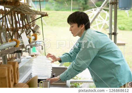 A young man filling a tank with water at a campsite kitchen 126868612