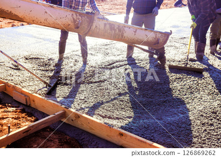 Construction crew expertly pours fresh concrete slab to create strong foundation for new building during works day 126869262