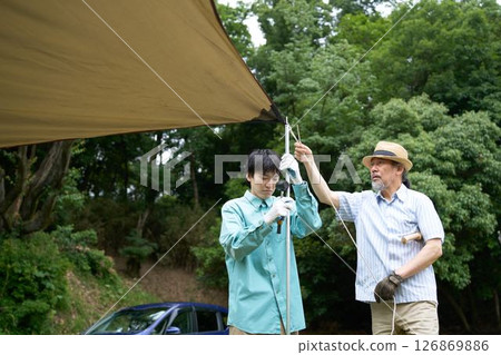 Camping friends setting up a tarp Camping friends setting up a tarp 126869886