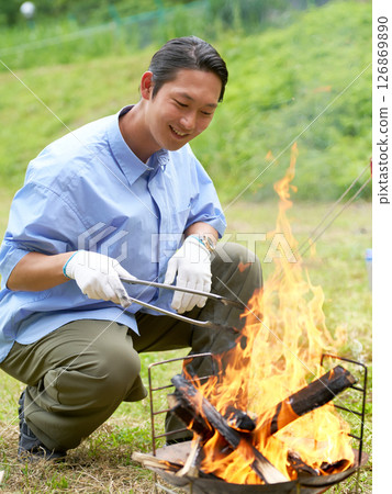 Smiling man adjusting a bonfire 126869890