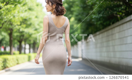 A style shot of a woman walking around town in a beige maxi dress A style shot of a woman walking around town in a beige maxi dress 126870541
