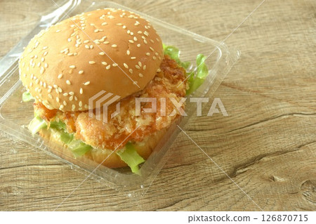 fried mashed shrimp hamburger and lettuce stuffed mayonnaise sauce with ketchup in plastic pakaging on table fried mashed shrimp hamburger and lettuce stuffed mayonnaise sauce with ketchup in plastic pakaging on table 126870715