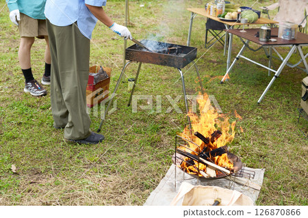 A man adjusting charcoal at a campsite 126870866