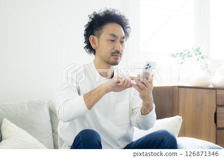 一名男子低頭看智慧型手機 126871346