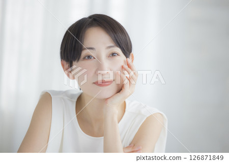 Middle-aged woman doing skin care in the living room Middle-aged woman doing skin care in the living room 126871849