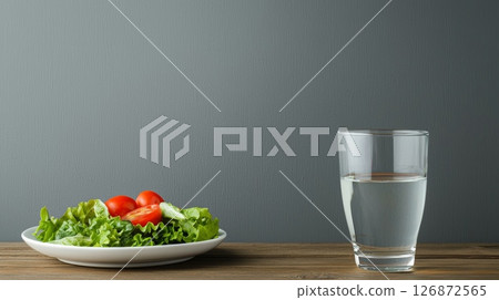 Healthy Lunch Break with Fresh Salad and Glass of Water on Wooden Table Against Gray Background 126872565