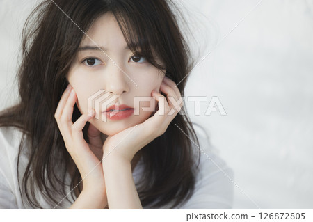 A woman thinking in front of a white wall 126872805