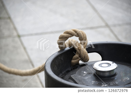Close-Up of Rope Tied Around Keg Outdoors on a Concrete Surface 126872976