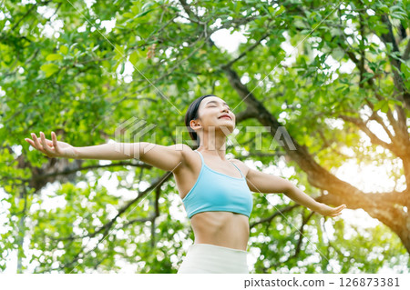 Young Asian woman relaxed breathing fresh air with trees in the background on a sunny day Young Asian woman relaxed breathing fresh air with trees in the background on a sunny day 126873381