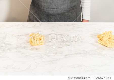 Front view of Classic Sugar Cookie Dough on a marble countertop, freshly mixed and ready for wrapping before chilling. The dough is lightly shaped, with the mixing bowl and spatula partially visible 126874055