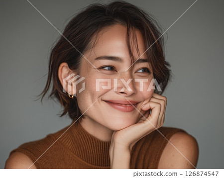 A gentle smiling woman resting her chin on her hand and looking at an angle 126874547