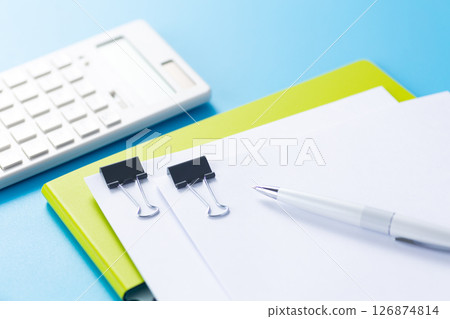 Documents clipped to a file, a calculator, and a ballpoint pen 126874814