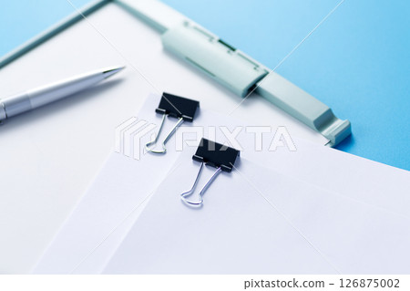 Documents clipped to a binder and a ballpoint pen 126875002