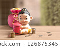 Money bag and thai girl child style of piggy bank with coins on the wooden table. 126875345