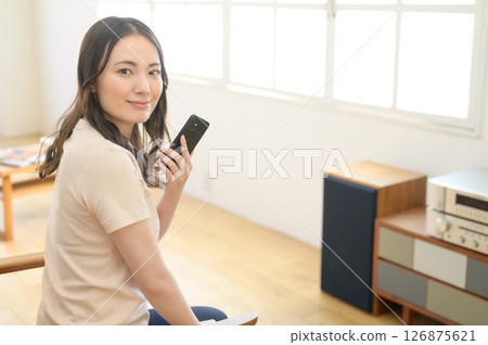 A woman listening to music while watching a smartphone 126875621