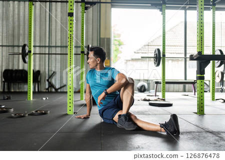 Fitness and Stretching. Man in a gym performing a seated stretch. 126876478