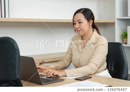 Focused Work Environment. Professional woman typing on laptop in modern office. 126876487