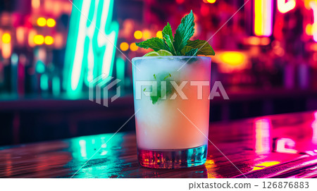 A frosty mojito cocktail with lime and mint on a bar counter, illuminated by vibrant neon lights 126876883