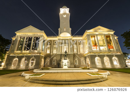Night view of the oldest Victoria Theatre and Concert Hall in Empress Place, Singapore, with a complex of two buildings and a clock tower. 126876926
