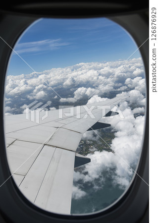 View of the plane's wing and beautiful clouds through the window during the flight. 126876929
