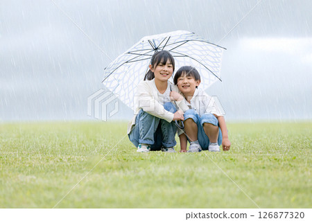 一個孩子在雨中撐著傘 126877320