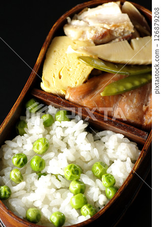 Bean and rice bento with plenty of side dishes photographed against a black background 126879208