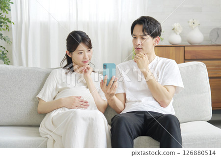 Pregnant wife and husband holding smartphones Pregnant wife and husband holding smartphones 126880514