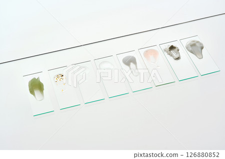 The textures of various cosmetic products on the slides are arranged diagonally in a single row. 126880852