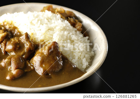 Chicken curry with large chunks of chicken photographed against a black background 126881265