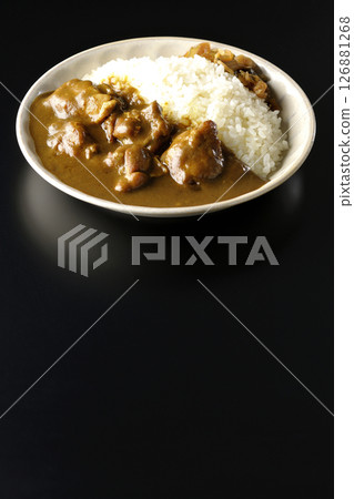 Chicken curry with large chunks of chicken photographed against a black background 126881268