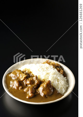 Chicken curry with large chunks of chicken photographed against a black background 126881269