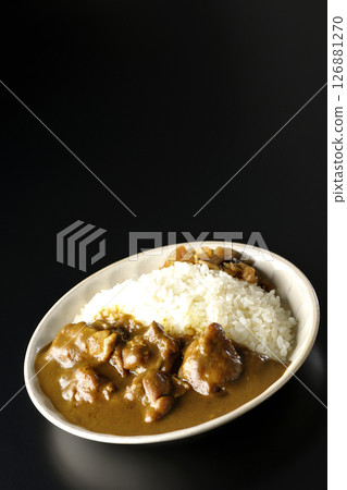 Chicken curry with large chunks of chicken photographed against a black background 126881270