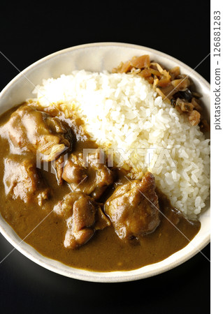 Chicken curry with large chunks of chicken photographed against a black background 126881283