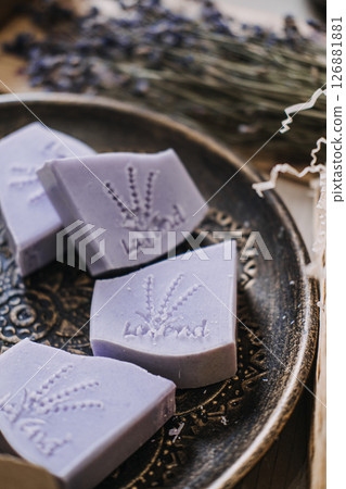Lavender soap bars with botanical stamps rest on a decorative plate beside dried flowers. Natural skincare, lavender soap, botanical self-care, eco-conscious beauty 126881881