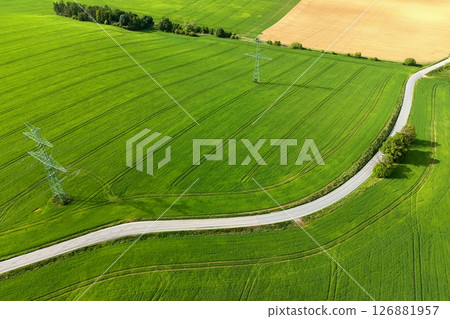Road with cars between green fields from above - view of nature from a drone. Beautiful landscape concept suitable for transportation, agriculture and environment. Road with cars between green fields from above - view of nature from a drone. Beautiful landscape concept suitable for transportation, agriculture and environment. 126881957