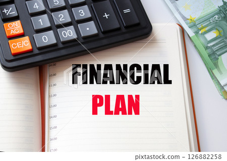 FINANCIAL PLAN word inscription in a notebook, calculator and a pile of money. 126882258