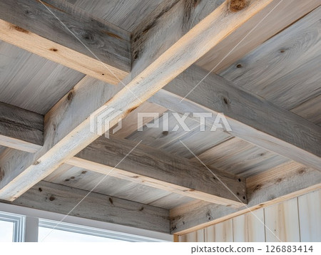 Rustic wooden ceiling beams with natural textures and warm tones in a cozy interior space 126883414
