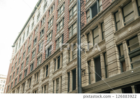 A detailed view of a classic red brick and beige stone building in New York. The architecture features large windows and vintage design. 126883922