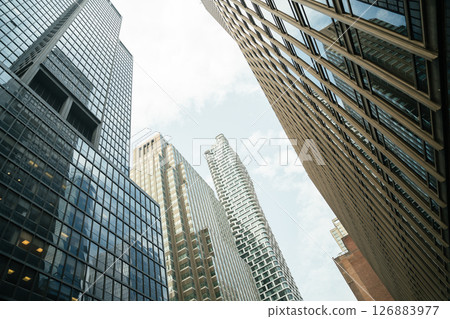 Looking up at a cluster of tall buildings in Midtown Manhattan. Glass reflections and urban geometry dominate the scene. 126883977